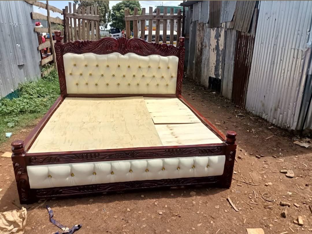 Carved mahogany bed with a cream and gold-button headboard
